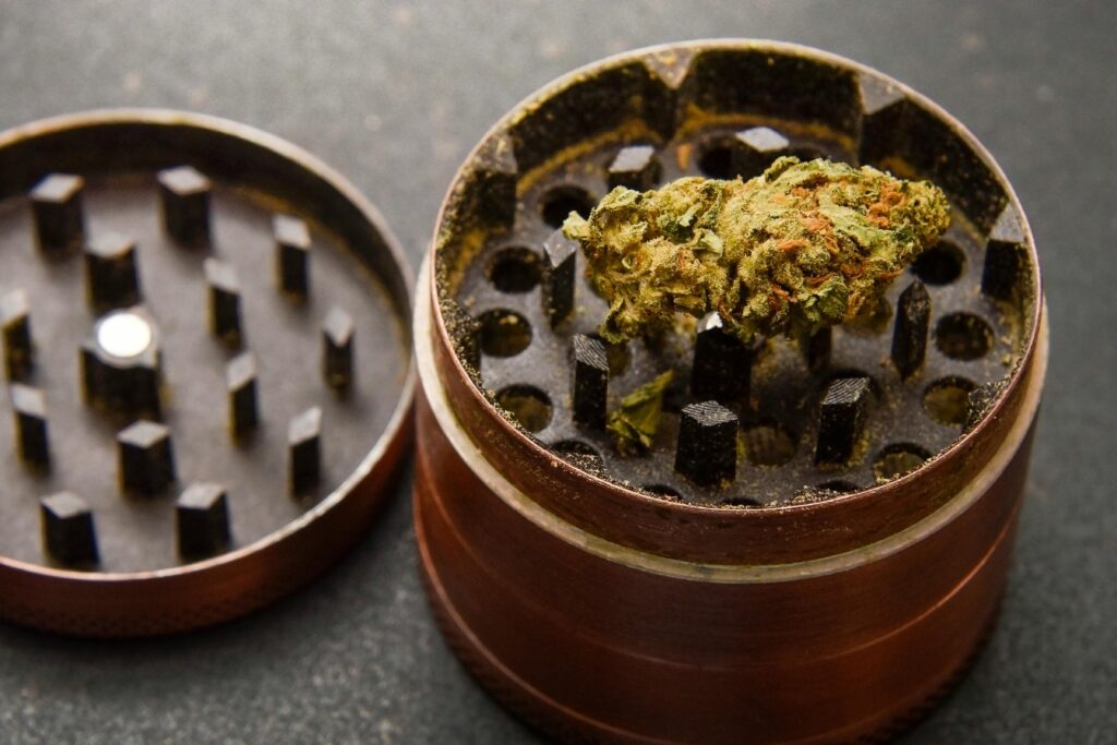 Close-up of cannabis bud in a marijuana grinder, showcasing texture and detail.